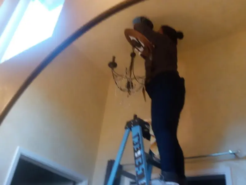 Electrician installing a chandelier in a Walsenburg residence